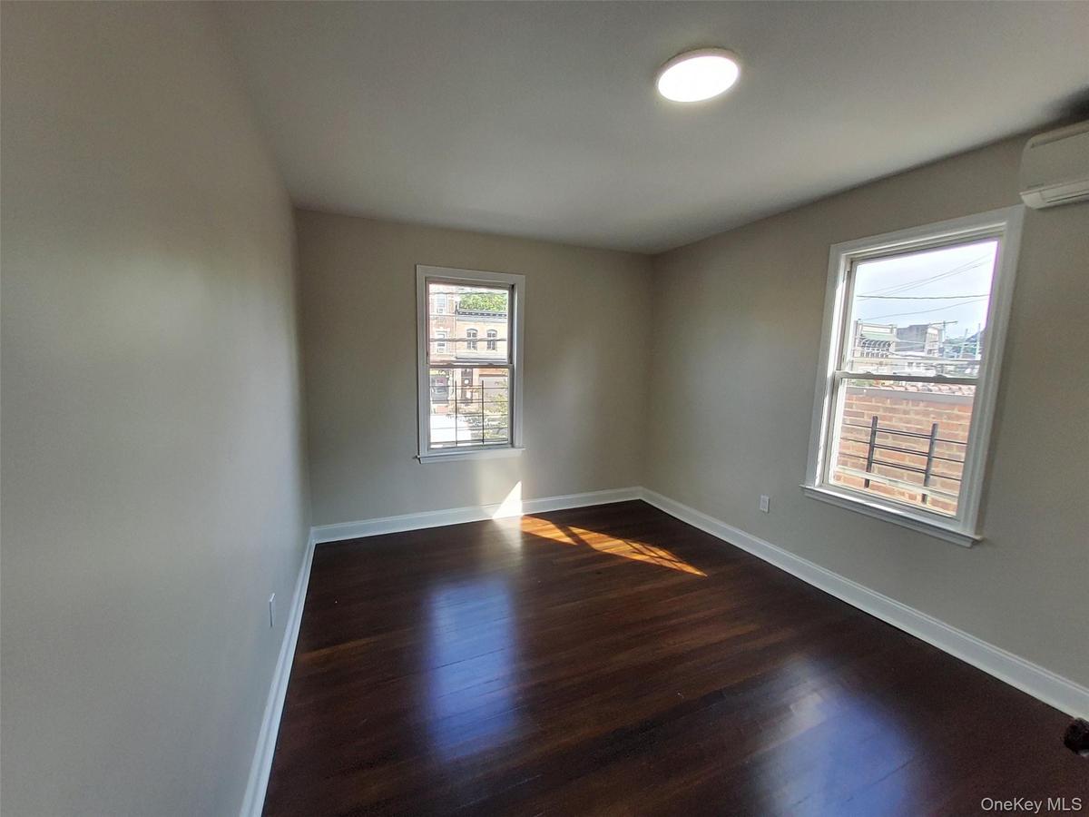 Empty room with a wall mounted air conditioner and dark hardwood / wood-style floors
