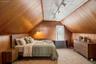 Attic space featuring wood paneling on walls and sloped ceilings, along with a white panel ceiling