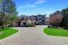 View of front of home featuring a front yard, stucco siding, curved driveway, and a chimney