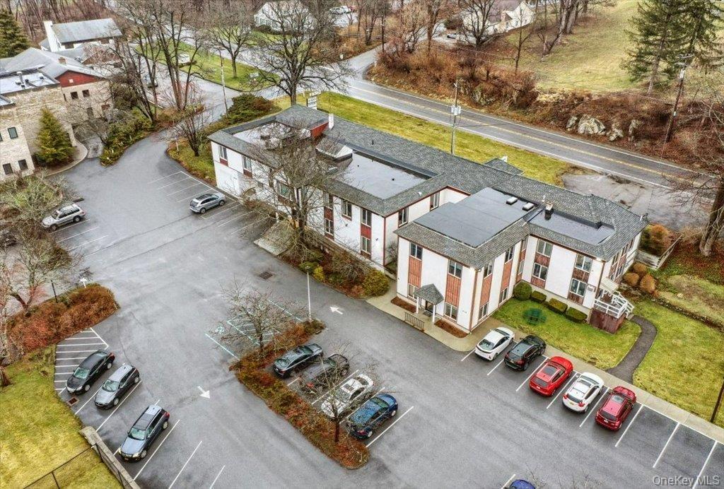 Commercial building featuring a large asphalt parking area with designated spaces, and a gravel-covered roof