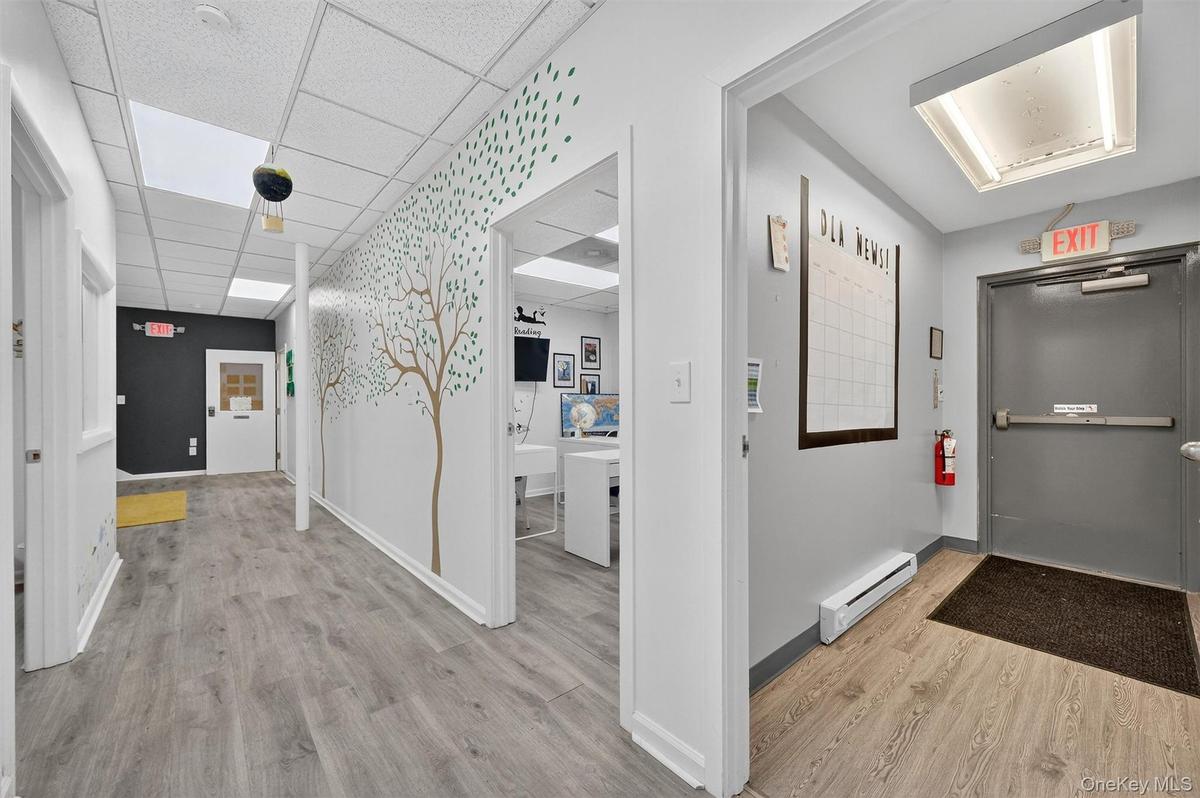 Hallway featuring wood-finish flooring, drop ceiling with recessed lighting, and white painted walls