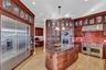 Kitchen with reddish brown cabinets, decorative light fixtures, under cabinet range hood, built in appliances, and light wood-type flooring