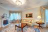 Living room with crown molding, a fireplace with raised hearth, wainscoting, and wood finished floors