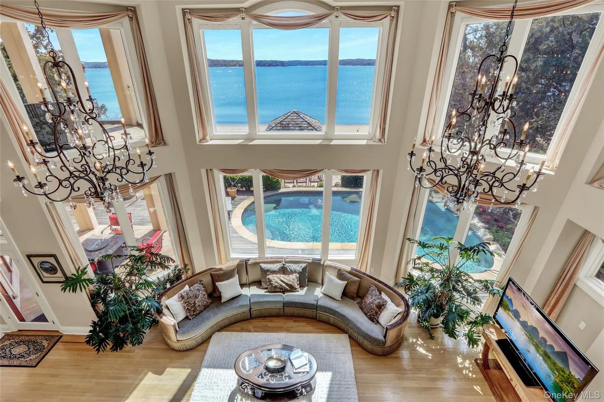 Living room with a high ceiling, wood finished floors, an inviting chandelier, and a water view