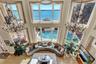 Living room with a high ceiling, wood finished floors, an inviting chandelier, and a water view