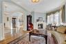 Living room featuring decorative columns, wood finished floors, a lit fireplace, and crown molding