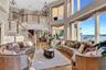 Living room featuring an inviting chandelier, stairway, wood-type flooring, ornamental molding, and a towering ceiling