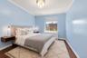 Light-filled room featuring hardwood flooring, crown molding, a window with a roller shade, and a built-in heating unit