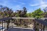 Balcony featuring a concrete surface, black metal railings, and a privacy wall
