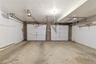 Two-car garage featuring concrete flooring, white overhead doors, and exposed brick accents