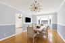 Dining area featuring wood-finish flooring, a contemporary sputnik-style chandelier, bay windows, two-tone painted walls with chair rail and crown mol