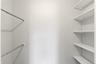 Bright storage space featuring adjustable white shelving and two chrome hanging rods
