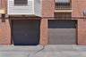 Two garage doors set within a brick facade, featuring paneled designs