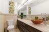 Vanity featuring a vessel sink with a contemporary faucet, expansive mirror, and accent lighting