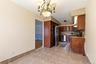 Kitchen featuring tile flooring, full-height tile backsplash, wood cabinetry, stainless steel appliances, and a granite-finish countertop