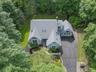 Expansive property featuring a multi-gabled roofline, light blue siding, and abundant surrounding greenery