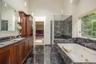 Bathroom featuring dark wood cabinetry, dual sinks, black veined stone countertops, and black veined stone flooring