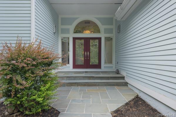 Exterior facade featuring light blue horizontal siding, a flagstone walkway, and flagstone steps leading to a dual red entry door with sidelights and 