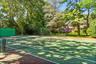 View of tennis court with view of wooded area