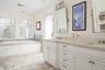 Full bath with double vanity, a sink, a healthy amount of sunlight, and ornamental molding