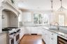 Kitchen featuring light wood-style flooring, beverage cooler, a sink, white cabinets, and range with two ovens