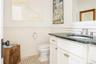 Bathroom featuring a wainscoted wall, toilet, vanity, and a decorative wall
