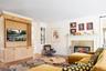 Living area with light wood-style flooring, baseboards, ornamental molding, and a tile fireplace