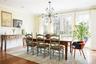 Dining area featuring a wainscoted wall, wood finished floors, a decorative wall, ornamental molding, and an inviting chandelier
