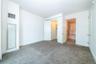 Primary bedroom with carpet flooring, a spacious walk in closet, and ensuite bath