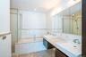 Bathroom with a garden tub, double vanity, tiled shower, and tile walls