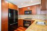 Kitchen with black appliances, wood finished floors, tasteful backsplash, light stone counters, and recessed lighting