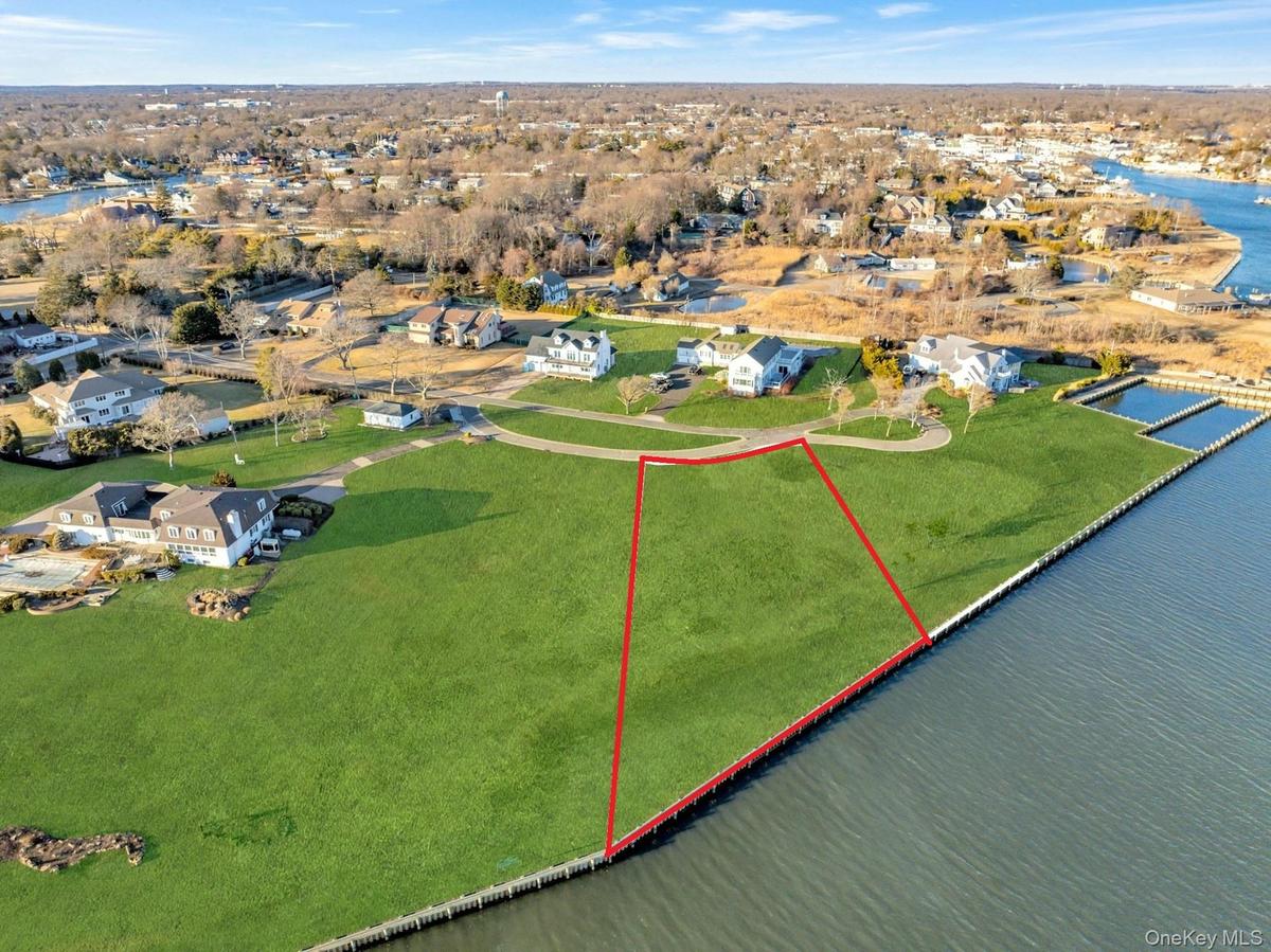 Aerial view of residential area with property parcel outlined and a nearby body of water