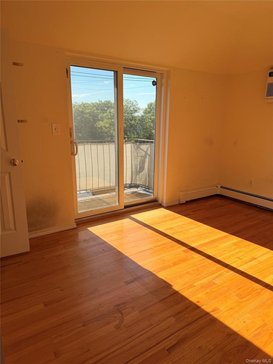Hardwood flooring throughout, featuring a sliding glass door leading to an outdoor balcony with metal railings