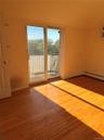 Hardwood flooring throughout, featuring a sliding glass door leading to an outdoor balcony with metal railings