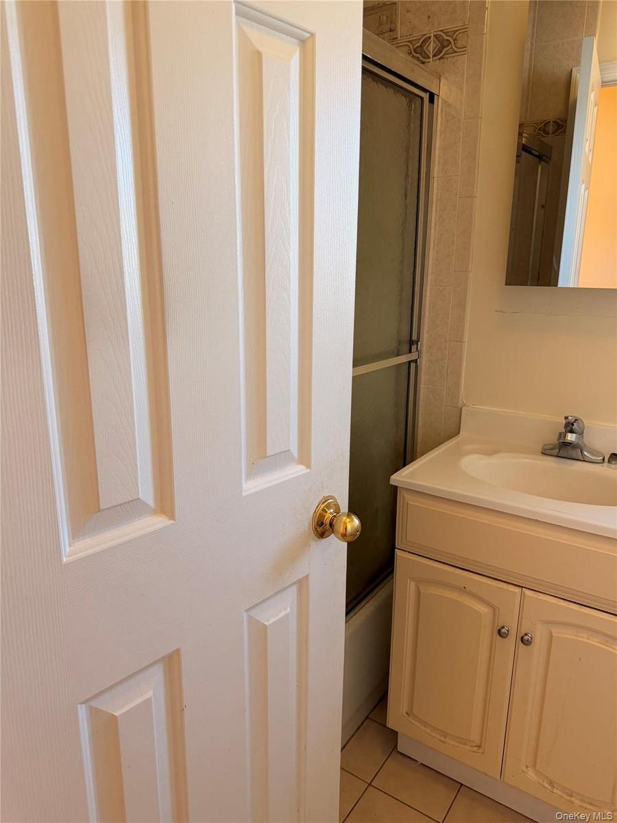 Bathroom vanity with integrated sink and chrome faucet, tile flooring, and a mirrored medicine cabinet