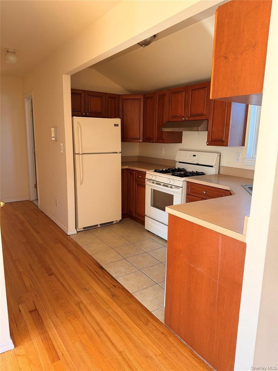Kitchen featuring wood-finish cabinetry, white appliances, and a light-toned countertop