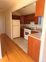 Kitchen featuring wood-finish cabinetry, white appliances, and a light-toned countertop