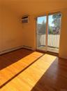 Room featuring wood-finish flooring, white baseboards, and a wall-mounted air conditioning unit