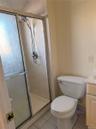 Shower enclosure with textured glass doors, tiled surround, and a detachable showerhead