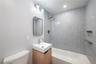 Contemporary bathroom featuring a light wood vanity with a white sink, faucet