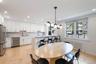 Open-concept kitchen and dining area featuring white shaker cabinetry, stainless steel appliances, a center island with bar seating, and parquet floor