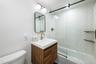 Bathroom featuring a wood vanity with a white rectangular sink, and a wall-mounted light fixture