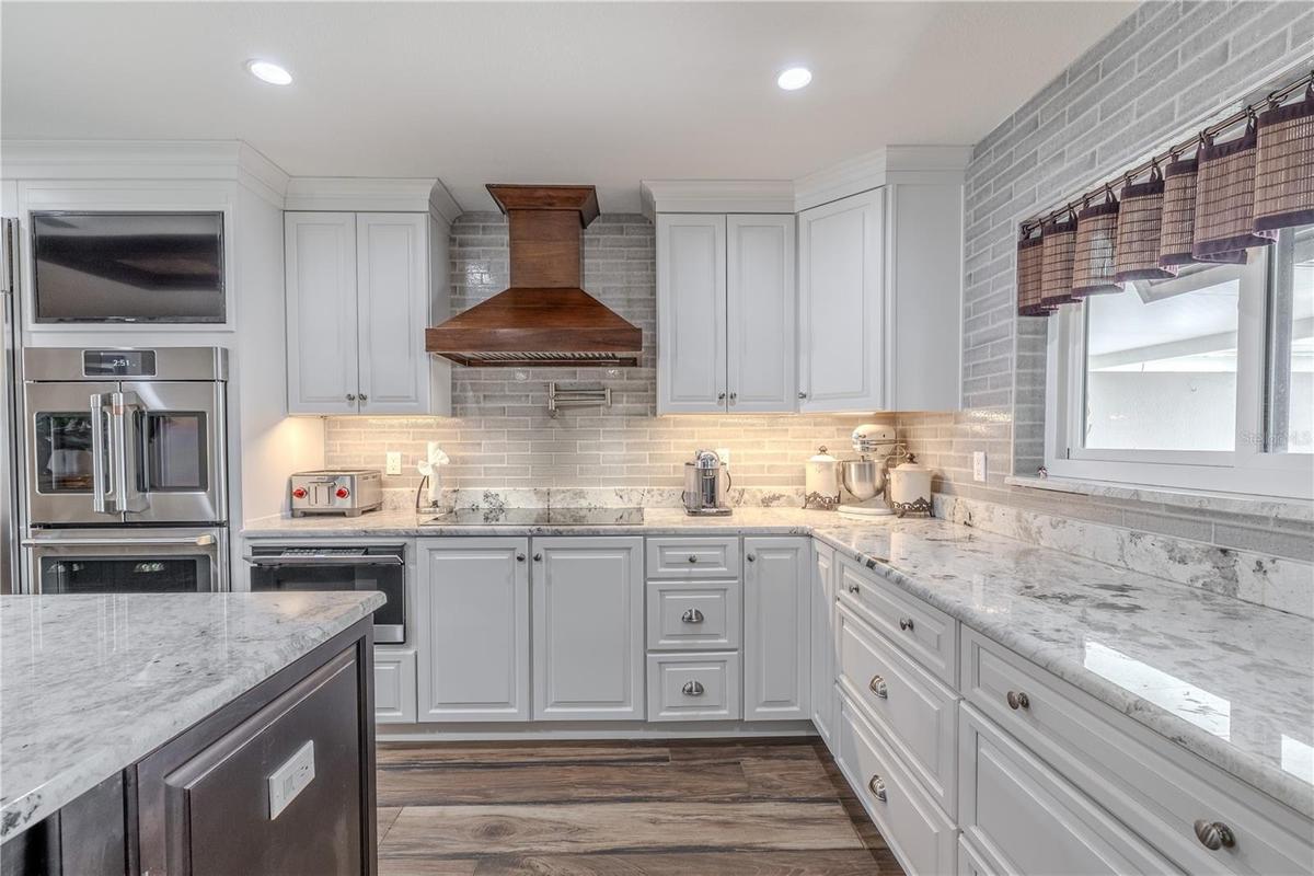 Elegant craftsmanship defines this kitchen, featuring a full brick-style backsplash, soft-close cabinetry, and polished granite counters.