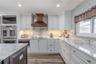 Elegant craftsmanship defines this kitchen, featuring a full brick-style backsplash, soft-close cabinetry, and polished granite counters.