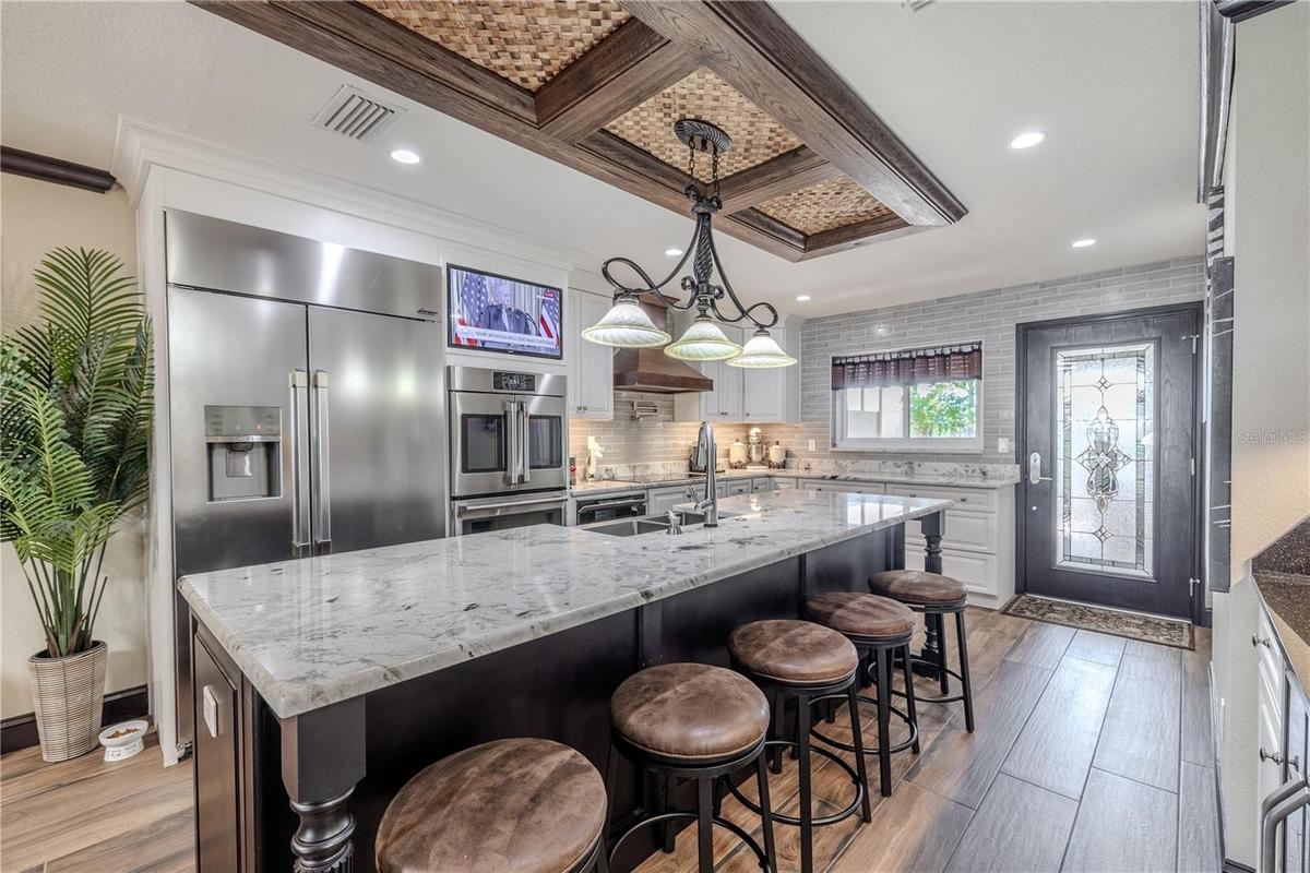 Custom cabinetry, under-cabinet lighting, and a pot filler combine functionality and style, while the built-in TV nook keeps the space perfect for ent