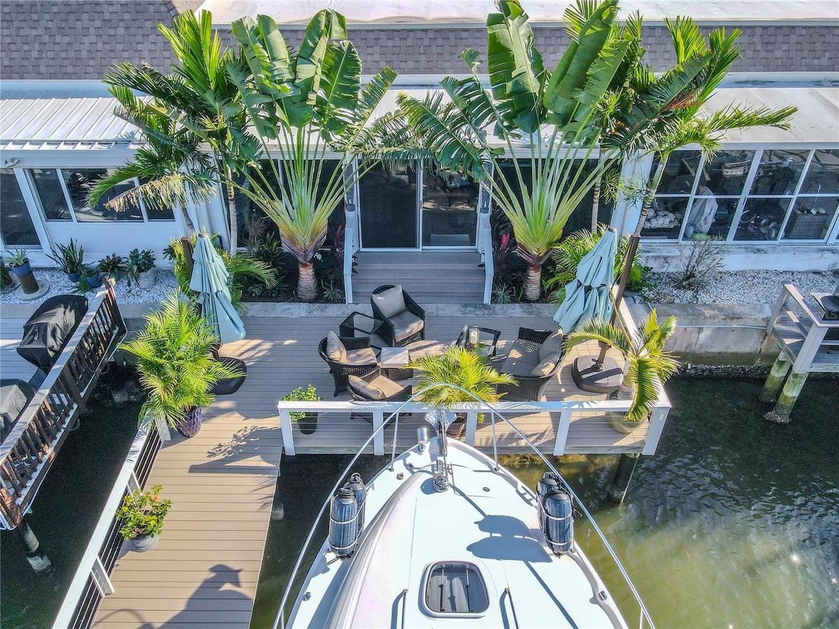 The spacious deck offers multiple seating areas for dining or sunbathing, framed by lush palms and scenic waterfront views.