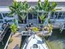 The spacious deck offers multiple seating areas for dining or sunbathing, framed by lush palms and scenic waterfront views.