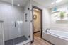 The primary walk-in shower features a rainfall showerhead, seamless glass enclosure, and elegant tile that extends floor to ceiling for a spa-like fin