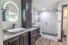 Relax in a spa-like setting featuring a jetted soaking tub, walk-in rainfall shower, and built-in linen storage that keeps everything beautifully orga