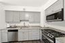 Contemporary kitchen featuring light gray cabinetry, granite countertops, and stainless steel appliances including an over-the-range microwave and a g